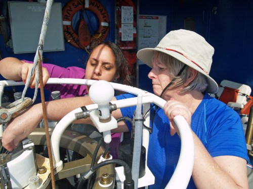 Green (left) learns to set the spring-loaded bottle plugs on a conductivity-temperature-depth sensor array with the help of Natalia Lopez Figueroa from Hampton University.